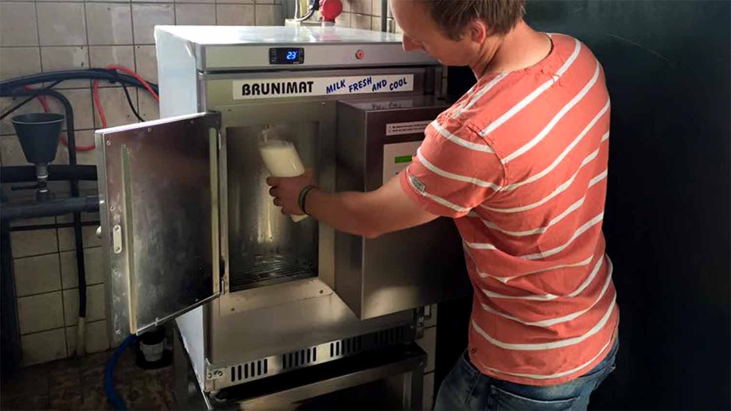 A person filling a glass jar from a Brunimat raw milk vending machine at Hoeve Bouwlust farm in Maasland, South Holland