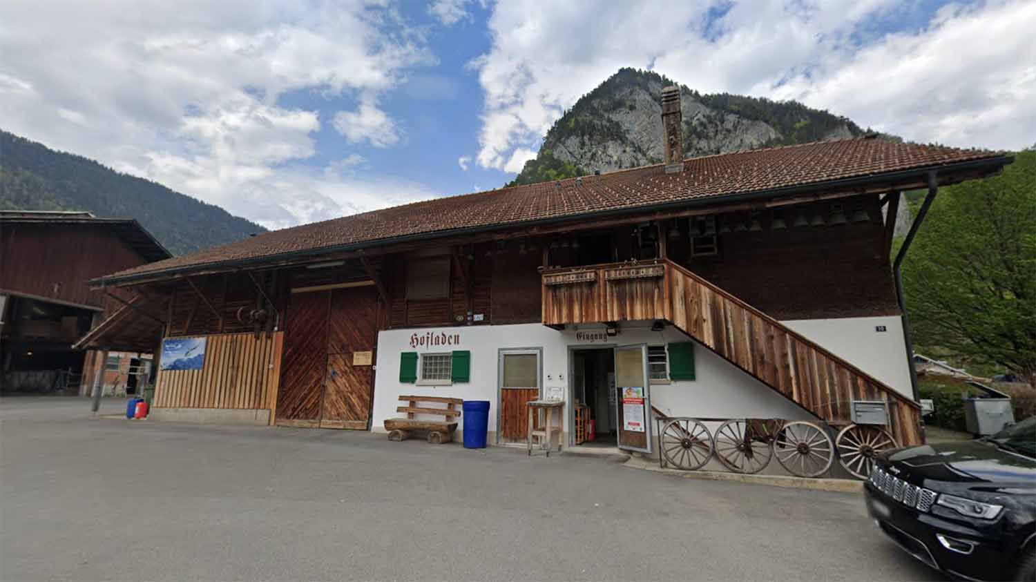 An Alpine Hofladen farm shop with traditional wooden architecture and mountain backdrop, of the kind that commonly houses raw milk vending machines in Switzerland and Austria