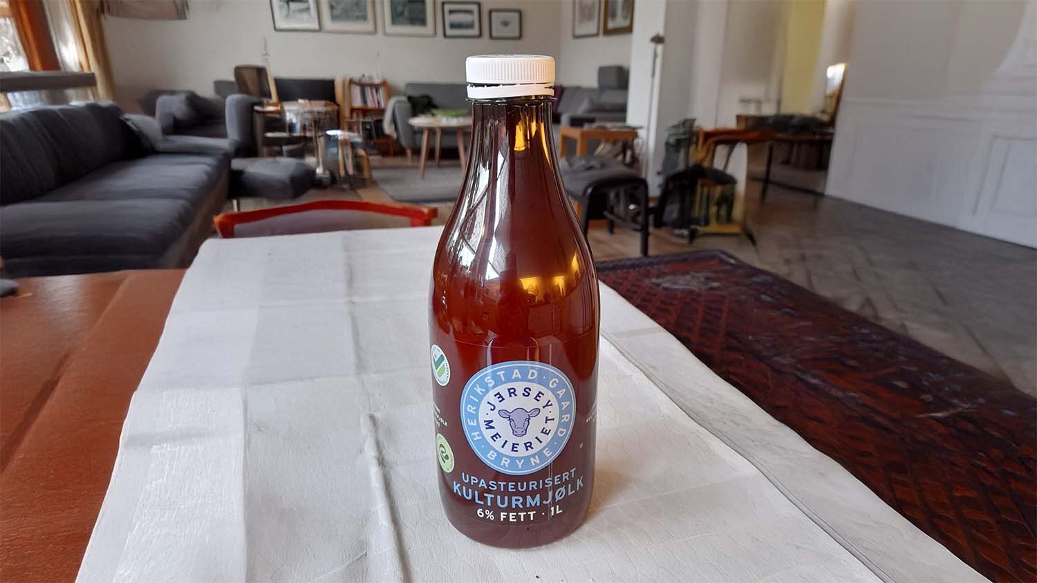 A 1 litre brown bottle of Jerseymeieriet Upasteurisert Kulturmjølk, 6% fat, from Herikstad Gaard in Bryne, Norway, standing on a table.