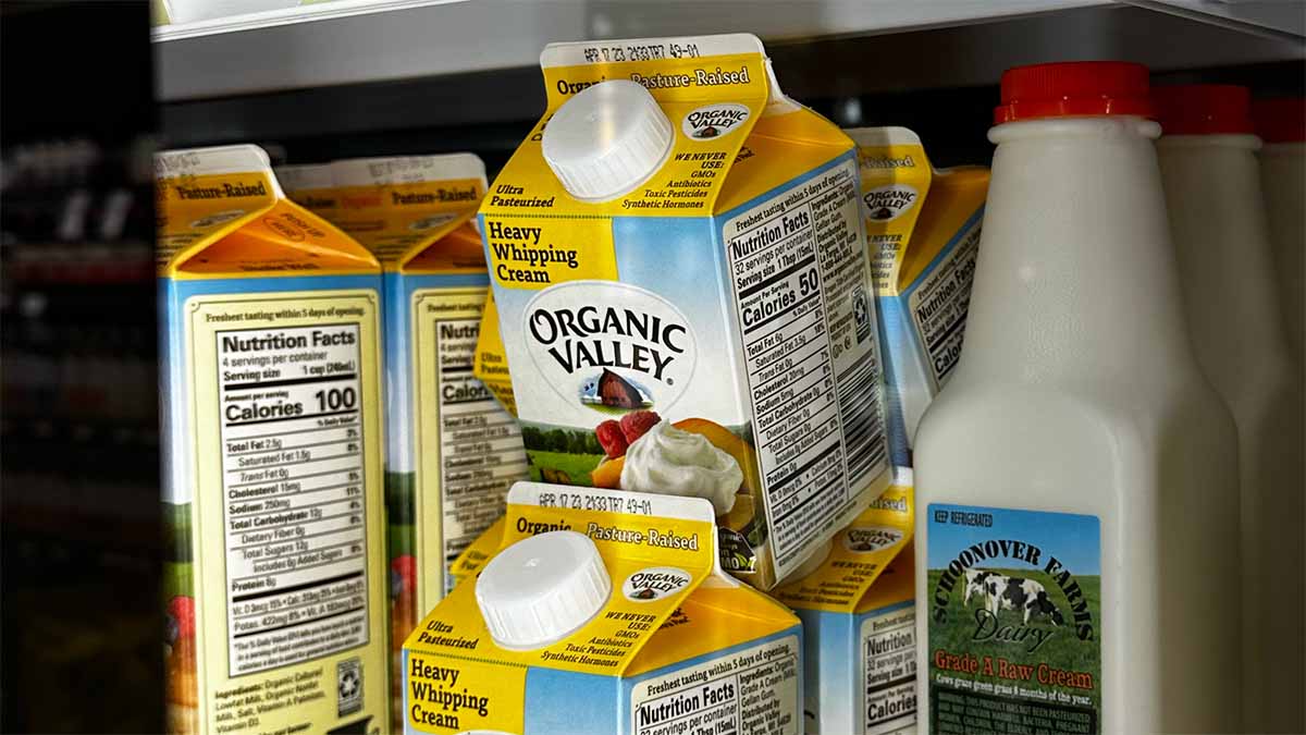 Organic Valley heavy whipping cream cartons next to Schoonover Farms raw cream in a refrigerated dairy case