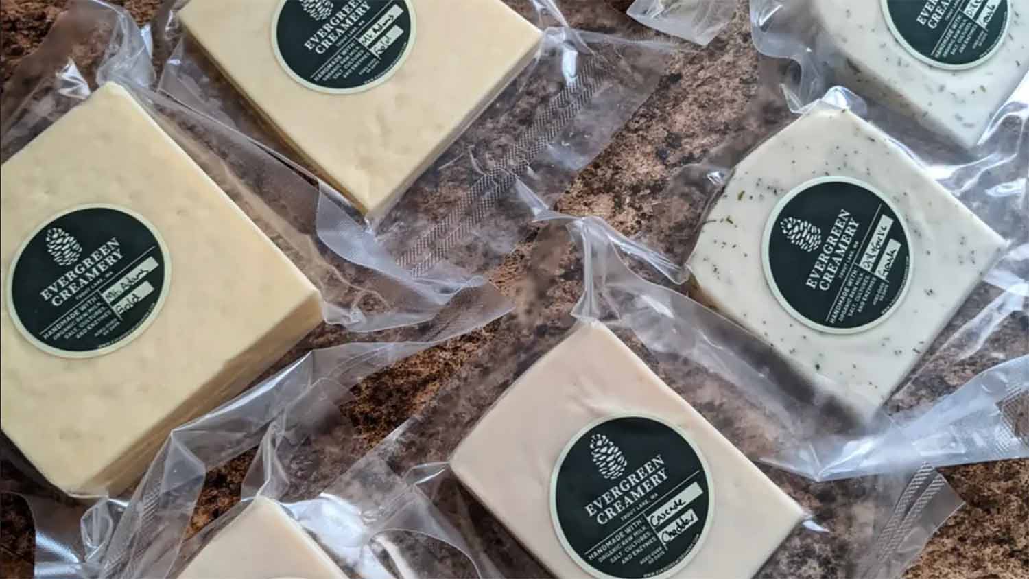 Vacuum-sealed blocks of Evergreen Creamery raw milk cheese from Trout Lake, Washington, labeled handmade with organic raw milk, salt, cultures and enzymes