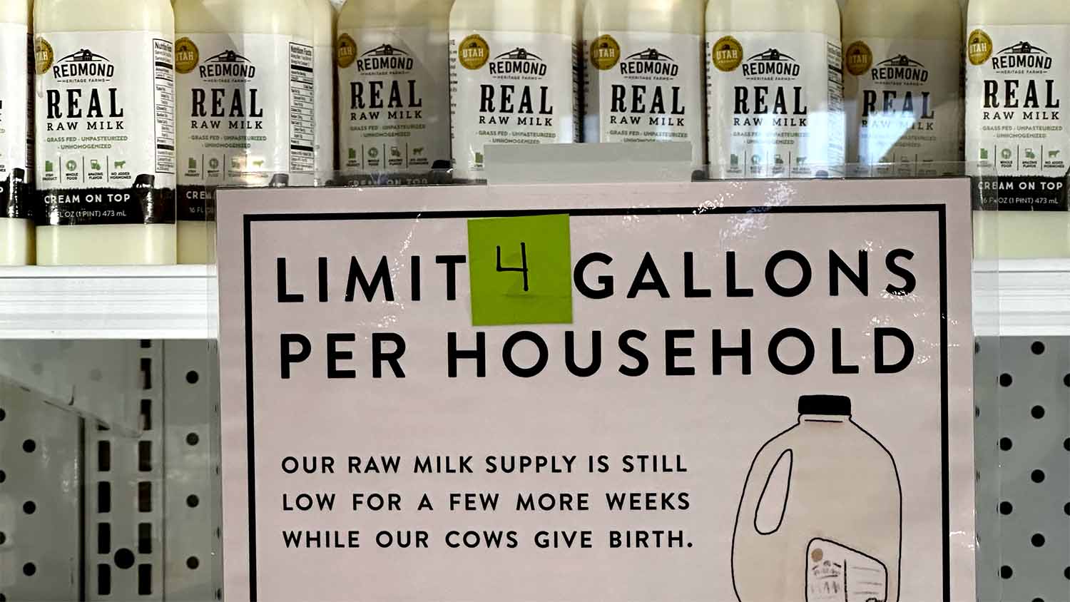Bottles of Redmond Heritage Farms raw milk on a Utah store shelf next to a sign explaining a temporary supply limit due to calving season.